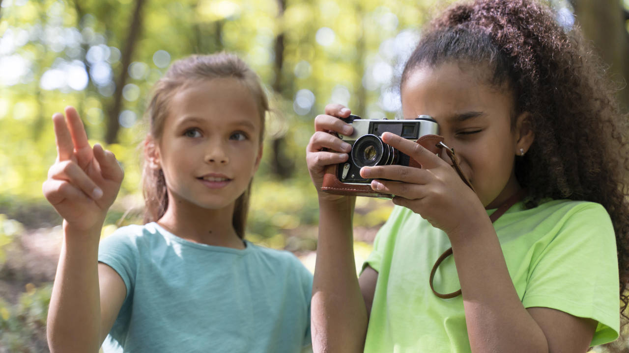 Meninas tirando fotos na natureza com câmera fotográfica infantil