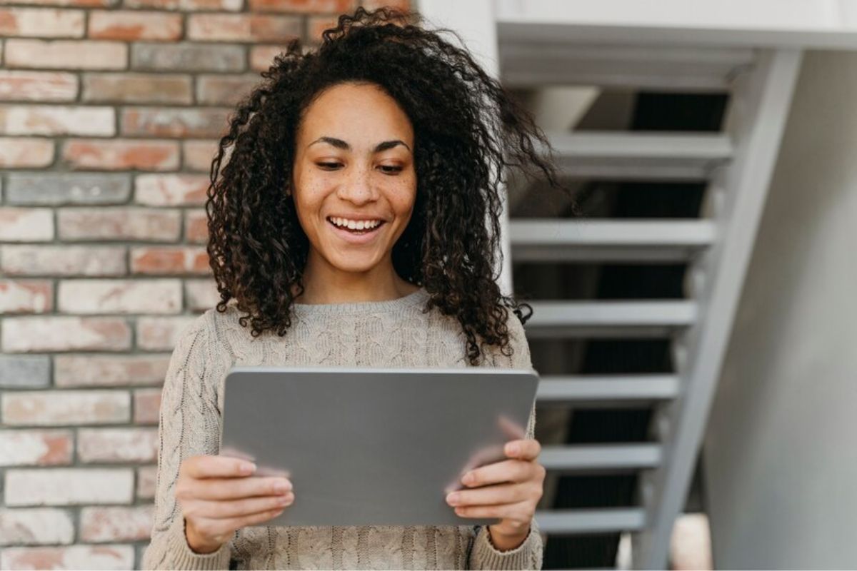 Uma mulher segura um grande tablet com duas mãos