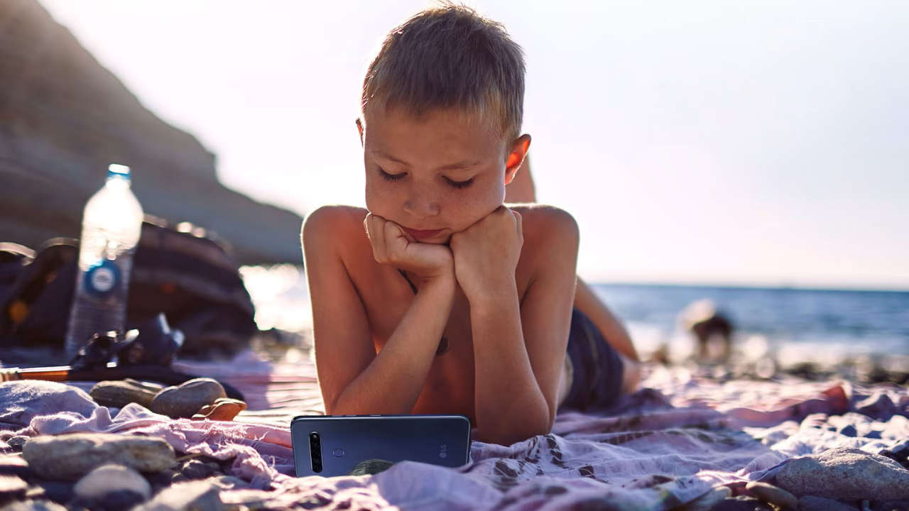 Garoto na praia com um LG K61, um dos piores celulares da empresa para comprar em 2025