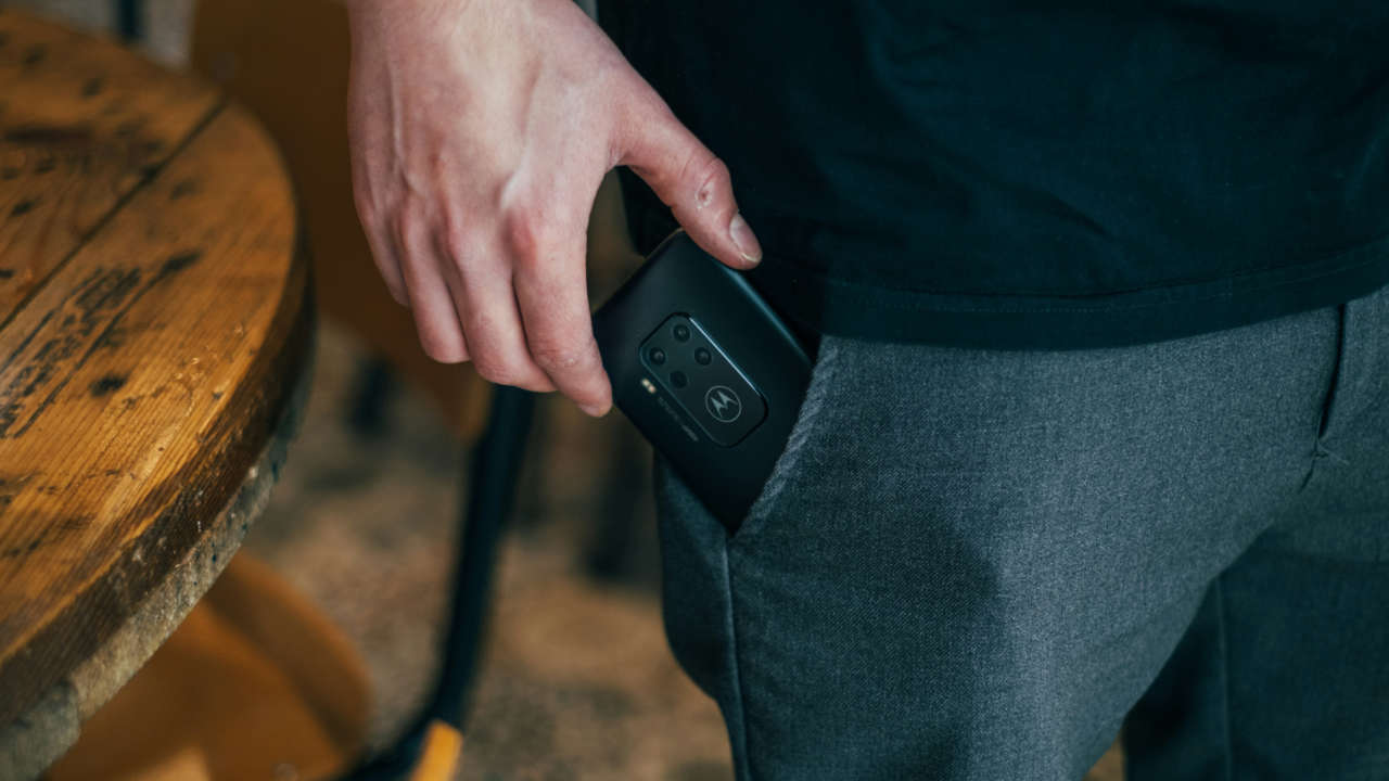 Homem tirando celular Motorola do bolso