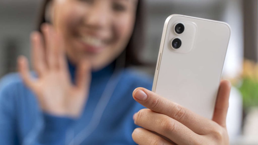 Mulher sorridente tirando uma selfie com um celular iPhone