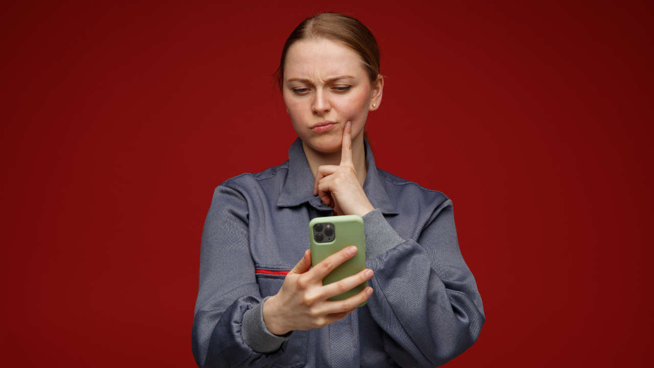 Mulher segurando celular com cara de desconfiada